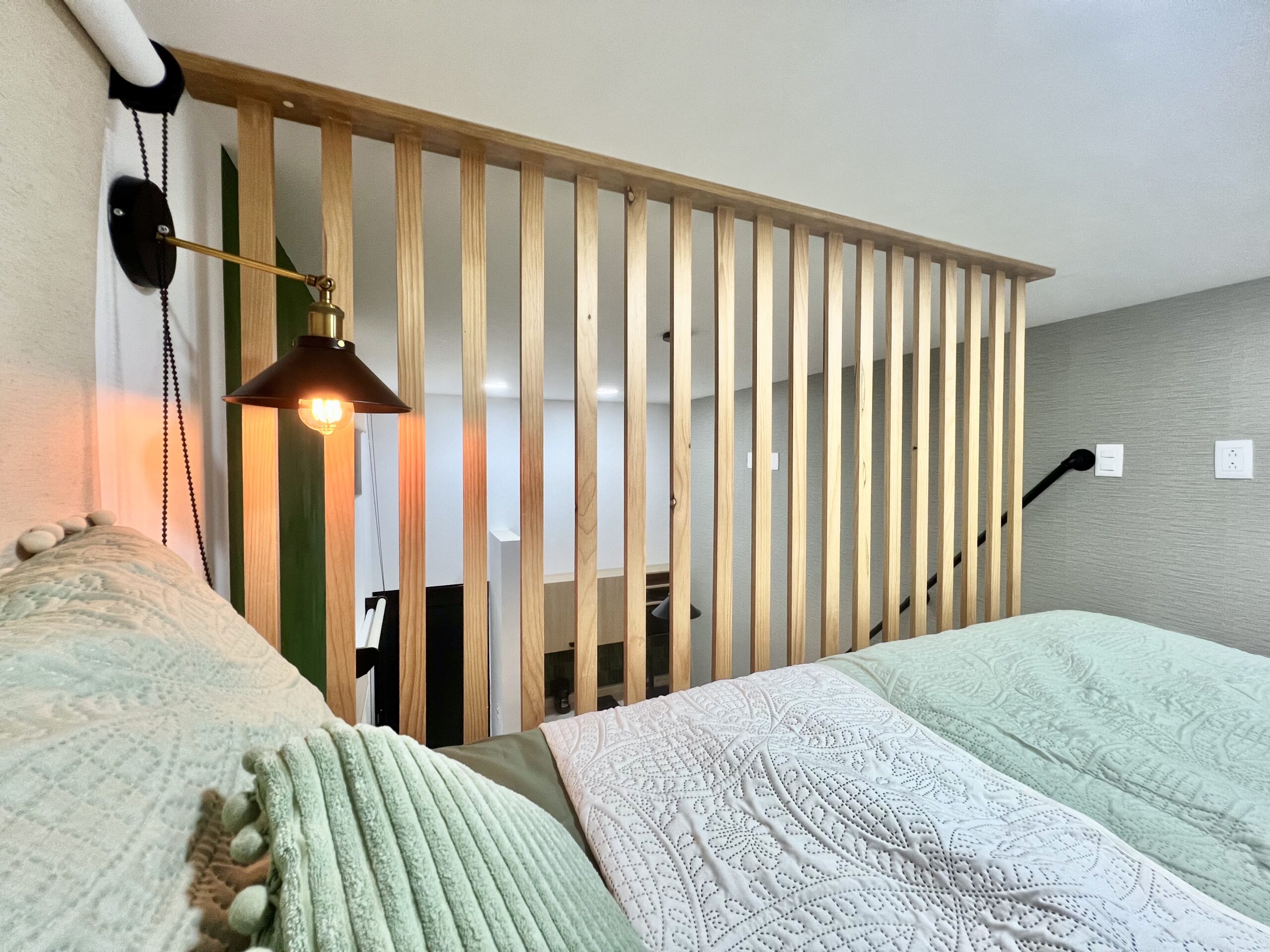 Dormitorio mezzanine de Verde Vid con cama, lámpara de lectura y barandal de madera